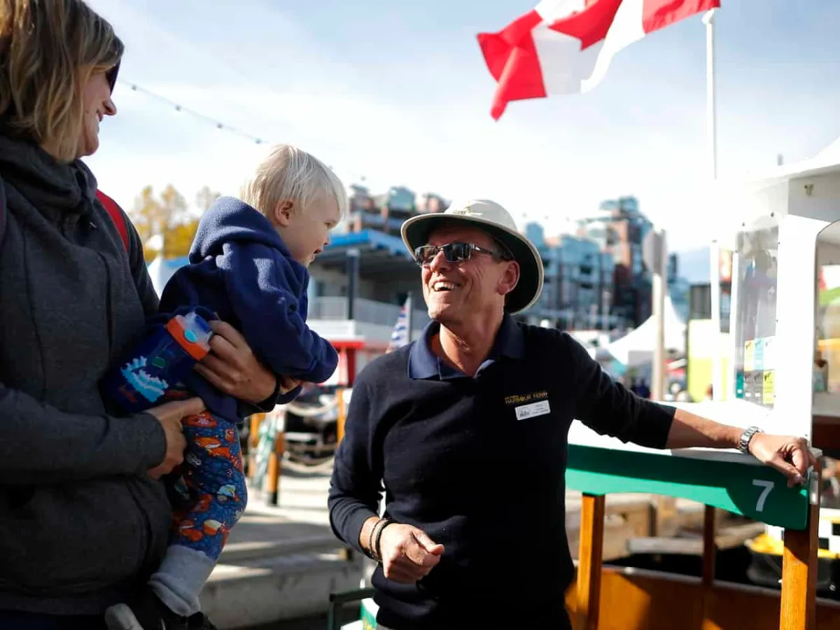 Captain holding a boat, smiling at a kid and parents, ready to board.