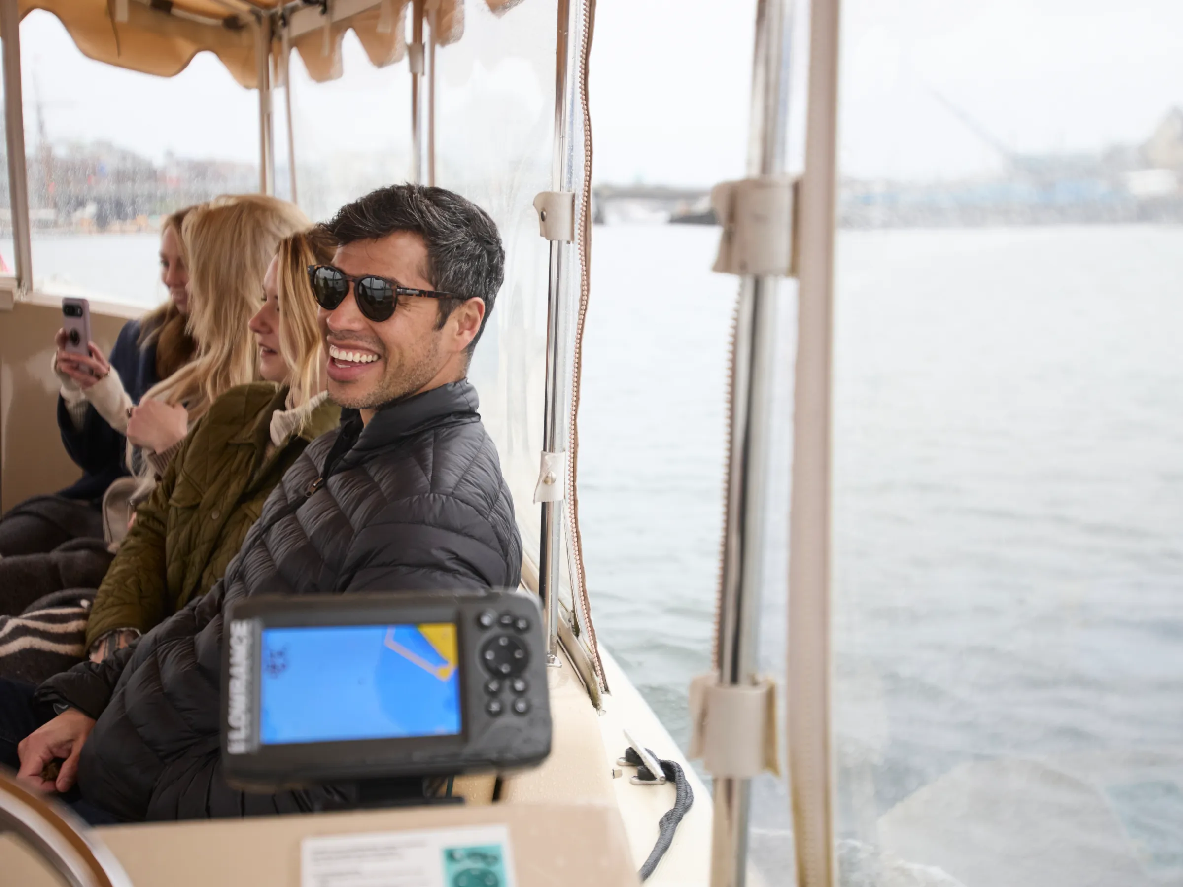 Smiling people on a boat, with water and GPS device visible.