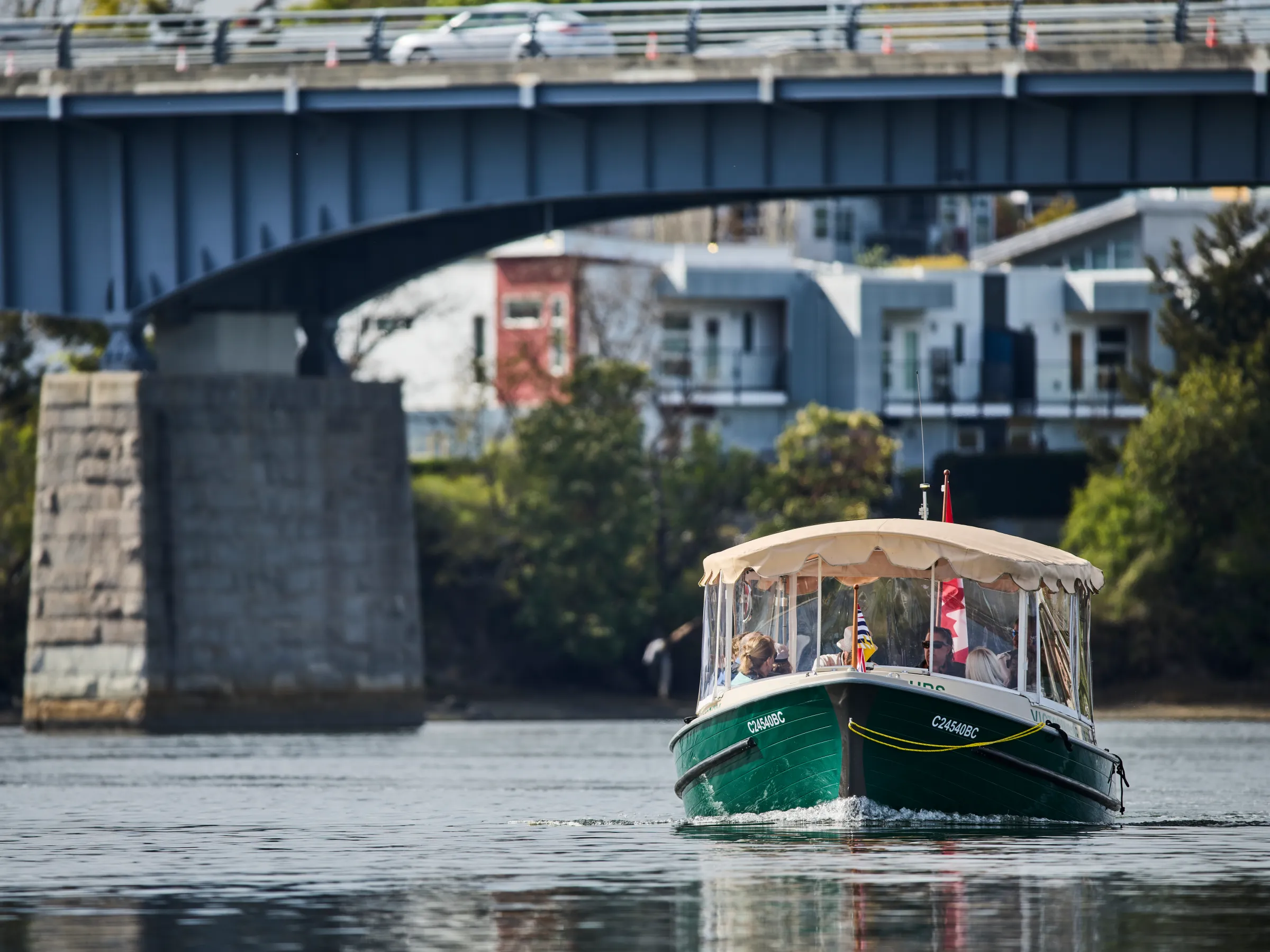 Small boat with passengers on water under bridge.